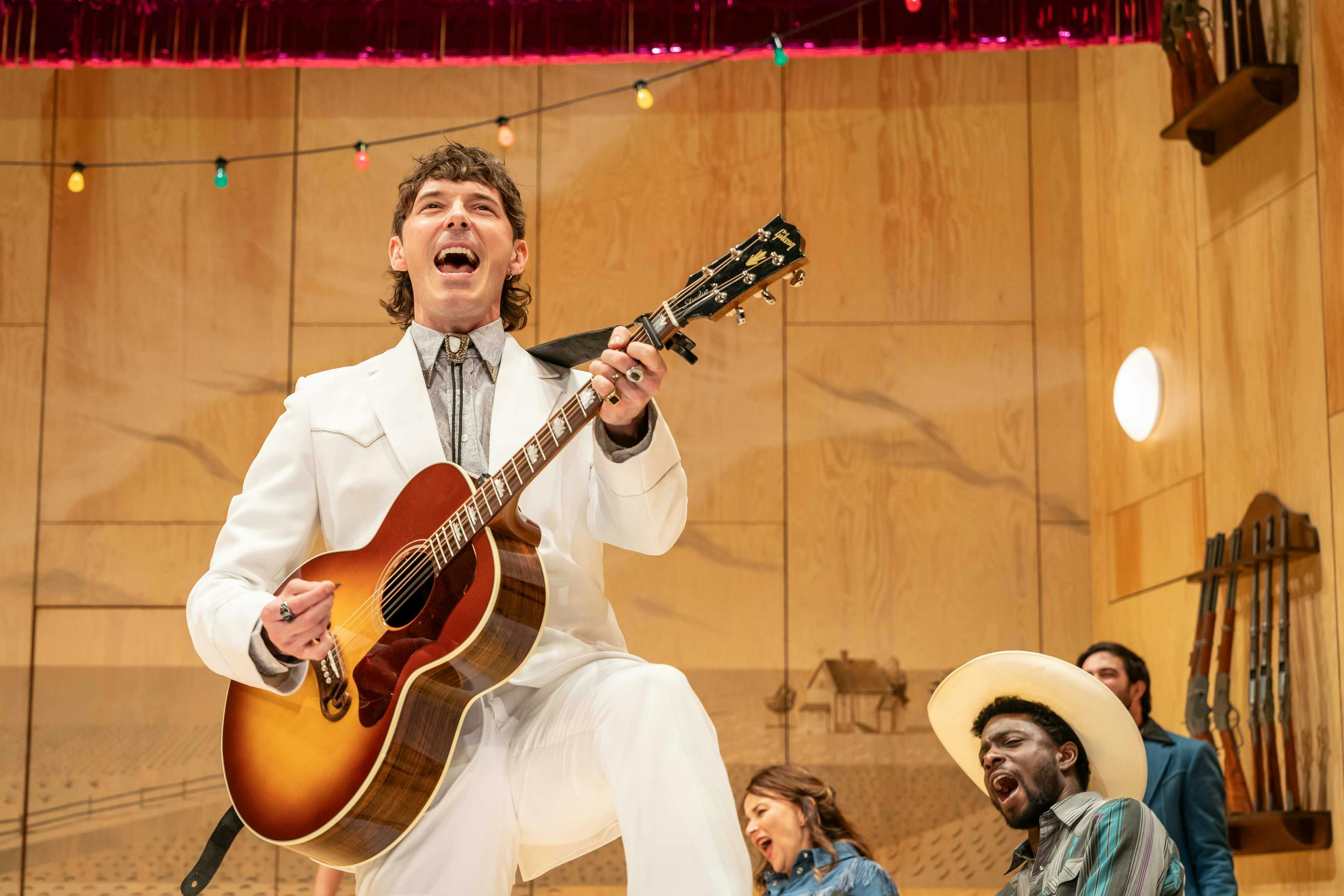 Oklahoma: The Musical - man singing and playing guitar on stage