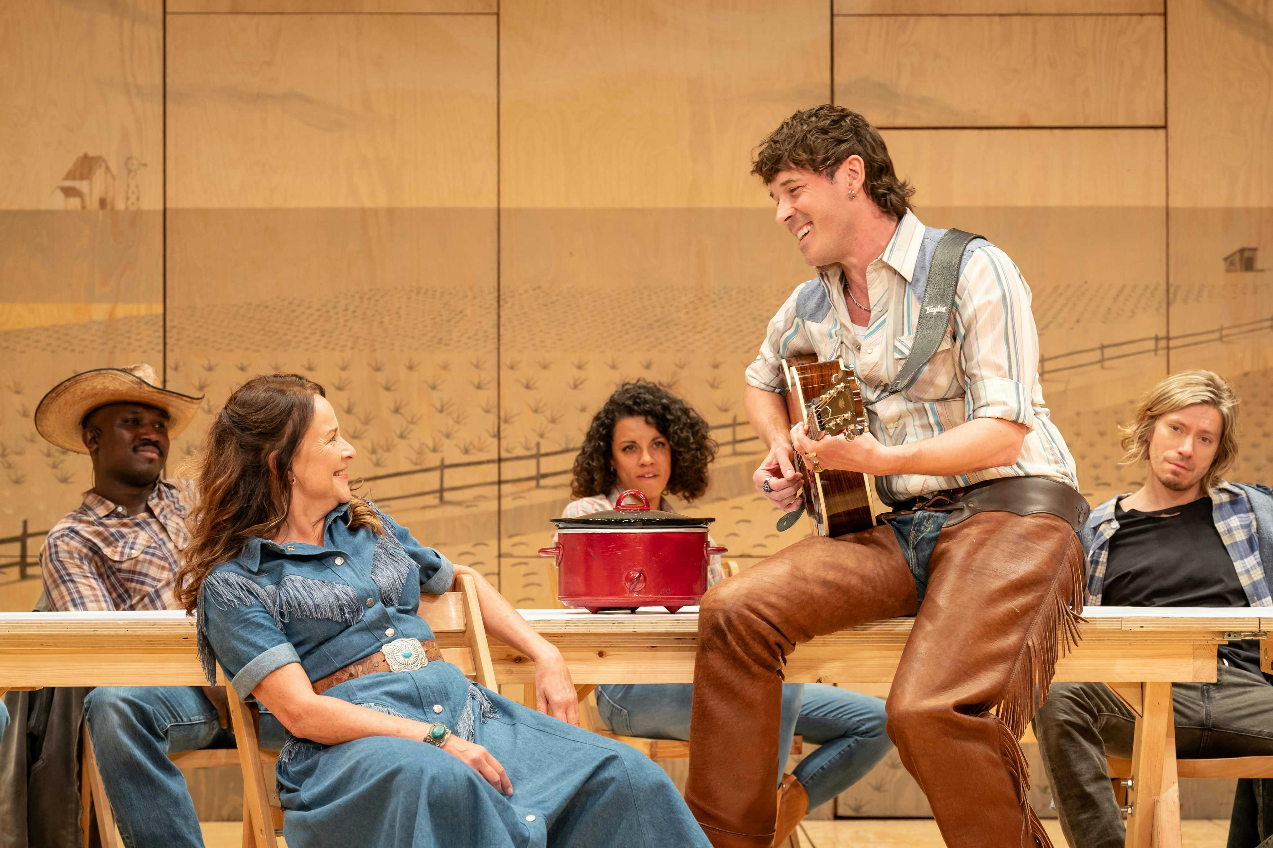 Oklahoma: The Musical - man holding a guitar singing to someone on stage