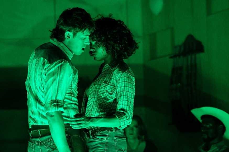 Oklahoma: The Musical - man and woman close together on stage in a green light