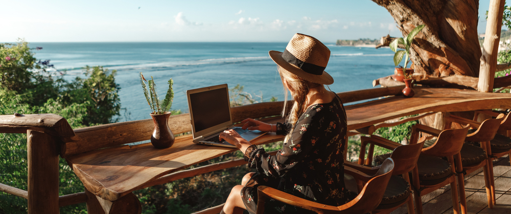 Person arbeitet an einem Laptop mit Blick aufs Meer