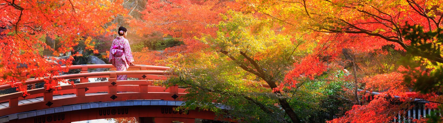 Lady walking over a bridge in Kyoto in autumn