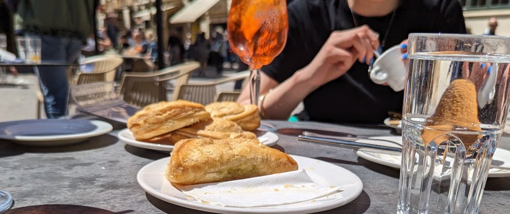 Ricotta and pea filled pastizzis, arancini, an Aperol spritz and a coffee being enjoyed at Caffe Cordina on Republic Square in Valletta