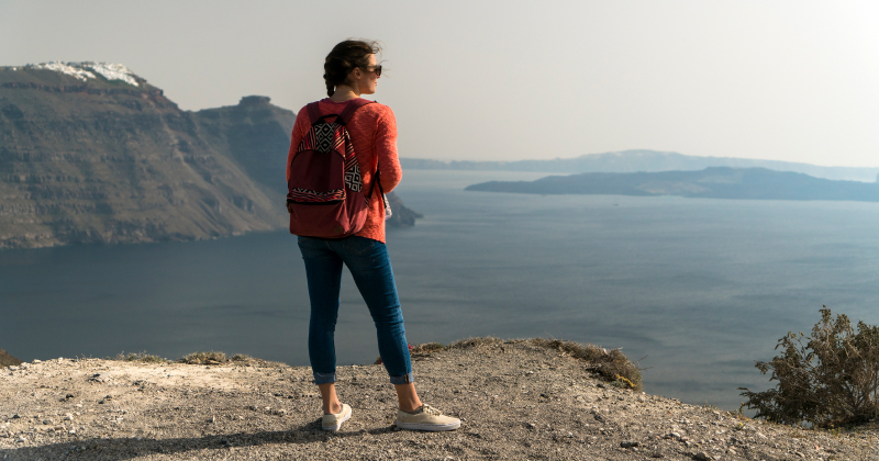 Person admiring view of the sea and mountains during a hike from Thira to Oia in Santorini, Greece