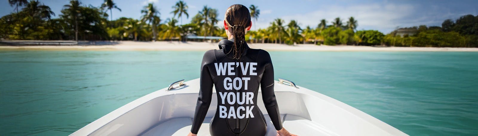 Woman on a surfboard with 'We've got your back' written on it in a tropical beach setting