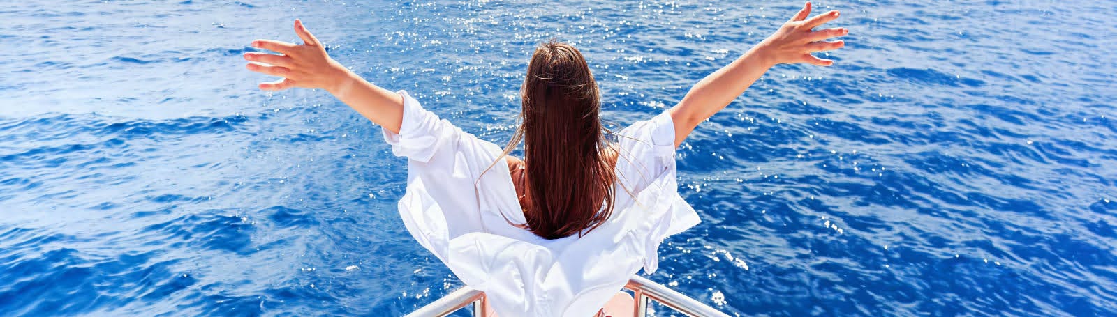 An aerial view of a cruise ship with a large pool deck visible at the rear, and a spacious area with lounge chairs and sunbeds.