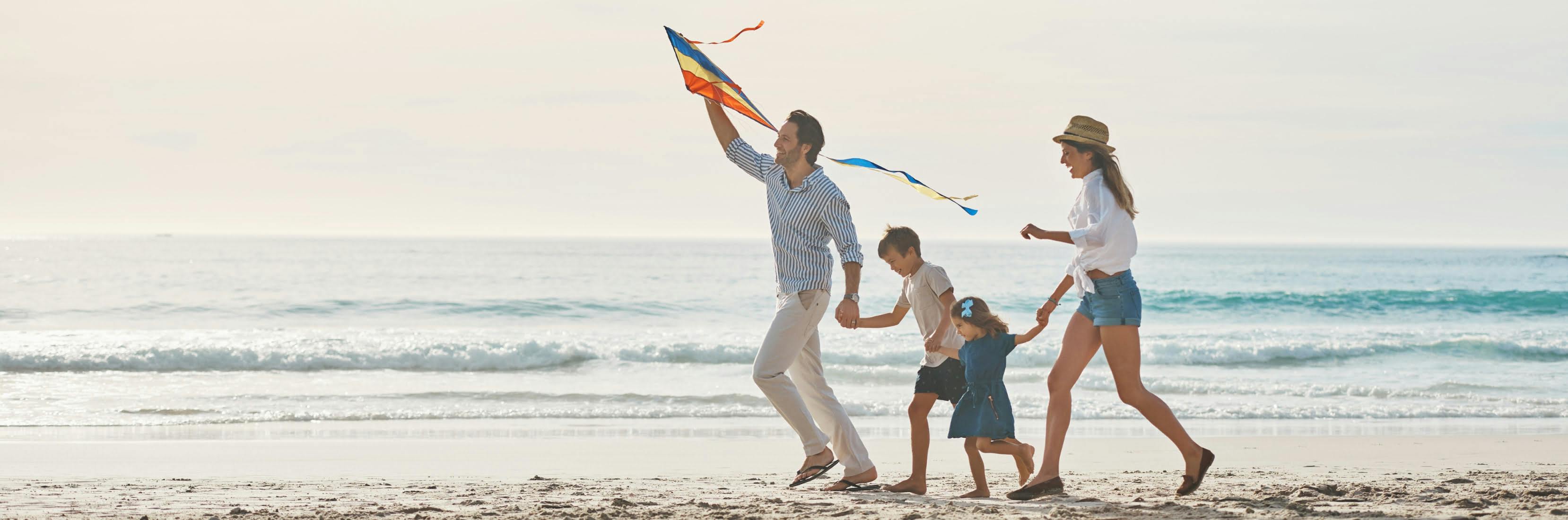 Happy family enjoying a beach holiday together, illustrating the benefits of family travel insurance for parents and children.