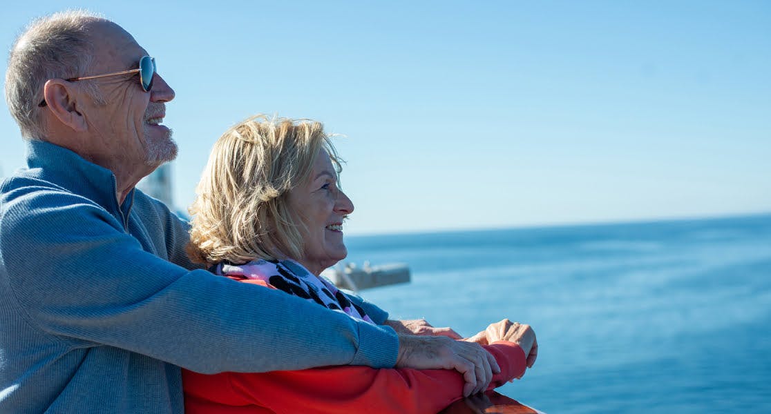 Smiling older couple enjoying scenic ocean views on a Fred Olsen cruise, covered by Fred Olsen cruise insurance for peace of mind.