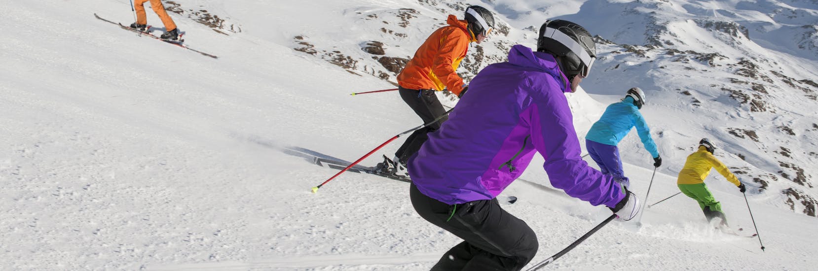 Person skiing down a snowy mountain slope surrounded by snow-covered trees on a bright winter day, highlighting the benefit of winter sports insurance