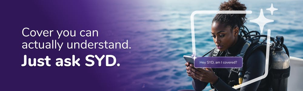 A woman in scuba diving gear, sitting on a boat, checking her phone.