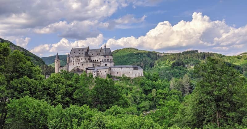 Vianden Castle in Luxembourg, surrounded by lush green forests and rolling hills