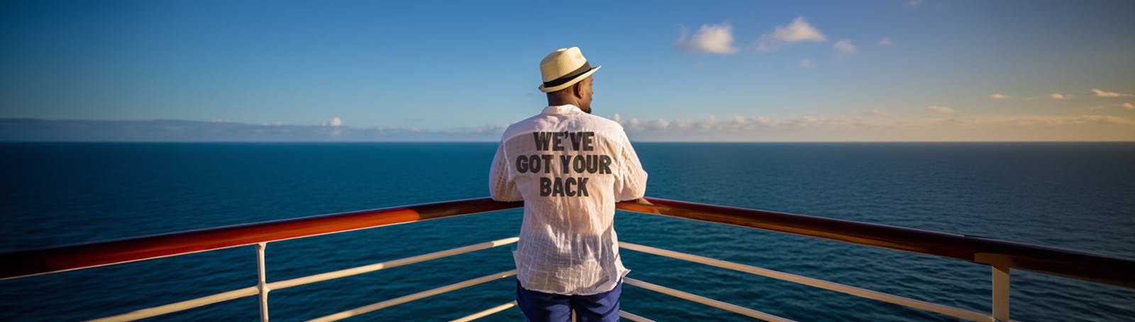 A young person stands on the beach at sunset, taking a photo of a group of friends who are posing with their arms raised. The photographer wears a T-shirt with the words 