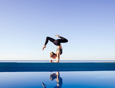 Frau macht Yoga am Pool