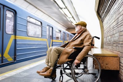 Älterer Mann im Rollstuhl an einem Bahnsteig