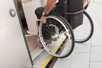 Person im Rollstuhl beim barrierefreien Einstieg in einen Zug.