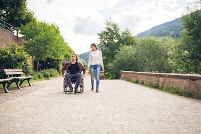 Freizeitangebote für Menschen mit Behinderung: Frau und Mann im Rollstuhl machen einen Ausflug im Park.