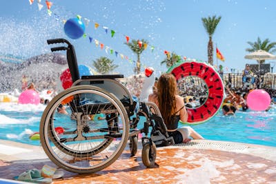Frau sitzt mit Rollstuhl am Pool