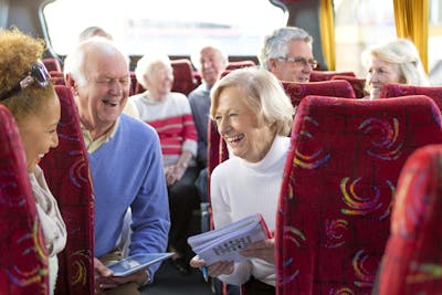 Reisen Senioren: Eine Seniorenreisegruppe sitzt im Reisebus und unterhaelt sich.