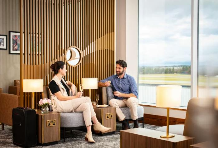 Two travellers relaxing beside the runway-view windows at Turkish Airlines Lounge by Plaza Premium Group, Edinburgh