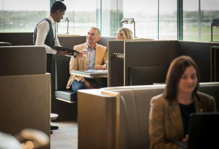 Seating booths, table service and a traveller using a laptop at Plaza Premium Lounge, Heathrow Terminal 5